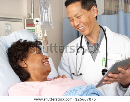 Doctor Using Digital Tablet Talking With Senior Patient