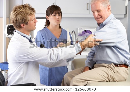 Doctor Examining Male Patient With Elbow Pain
