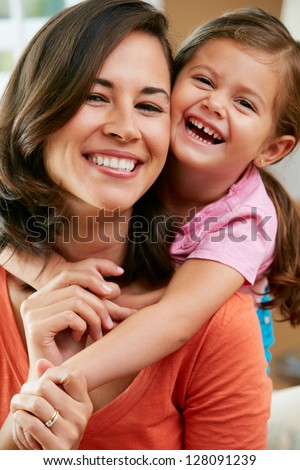 Portrait Of Mother And Daughter Sitting On Sofa At Home