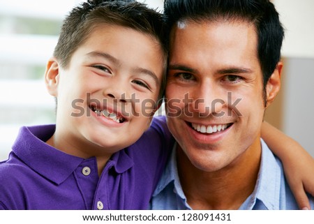 Portrait Of Father And Son Sitting On Sofa At Home