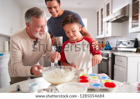 Dad watching his son making cakes with grandad at the kitchen table, close up