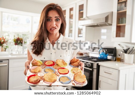 Millennial Hispanic woman presenting her cakes to camera after a baking disaster, close up