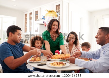 African American three generation family sitting together at the kitchen table, with grandmother serving food, close up