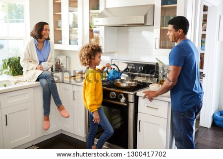 African American parents and their daughter spending time together preparing food in the kitchen