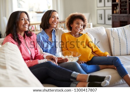 Three generation African American family female family group spending time together sitting on the sofa watching TV at home, selective focus