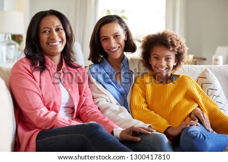Three generation African American family female family group sitting on a sofa in the living room smiling to camera, close up