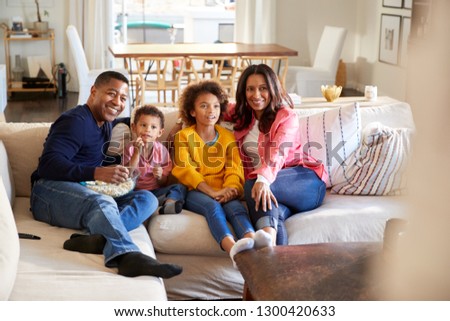 African American young grandparents sitting with their grandchildren on sofa in the living room watching TV, selective focus