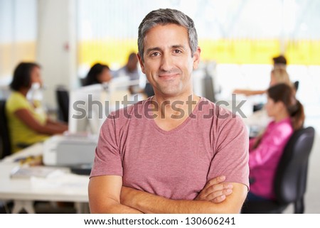 Portrait Of Man Standing In Busy Creative Office