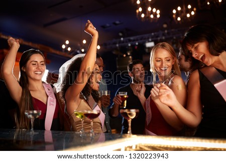 Group Of Dancing Female Friends Celebrating With Bride On Hen Party In Bar