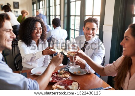 Business Colleagues Making Toast Sitting Around Restaurant Table Eating Meal