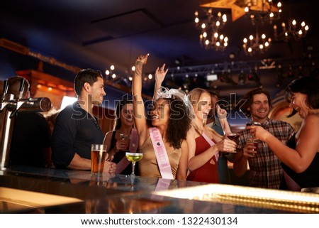 Group Of Dancing Friends Celebrating With Bride On Hen Party In Bar