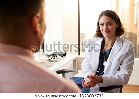Over The Shoulder View Of Man Having Consultation With Female Doctor In Hospital Office