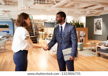 Businessman And Businesswoman Meeting And Shaking Hands In Modern Open Plan Office