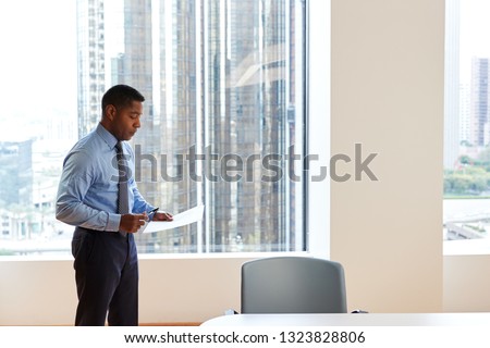 Mature Businessman Standing Rehearsing Before Giving Presentation In Modern Open Plan Office