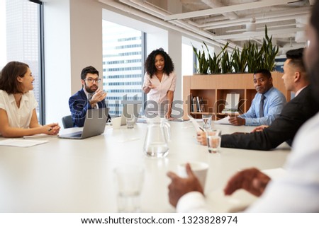 Businesswoman Standing Giving Presentation To Colleagues In Modern Open Plan Office