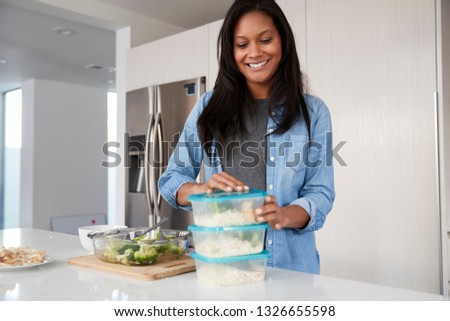 Woman In Kitchen Preparing High Protein Meal And Putting Portions Into Plastic Containers
