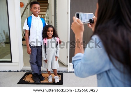 Mother Taking Photo Of Children With Cell Phone On First Day Back At School