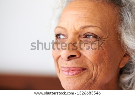 Close Up Of Smiling Senior Woman Sitting On Bed At Home Looking Positive