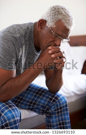 Depressed African American Senior Man Looking Unhappy Sitting On Side Of Bed At Home With Head In Hands