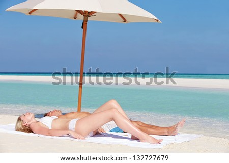 Couple Sunbathing On Beautiful Beach Holiday