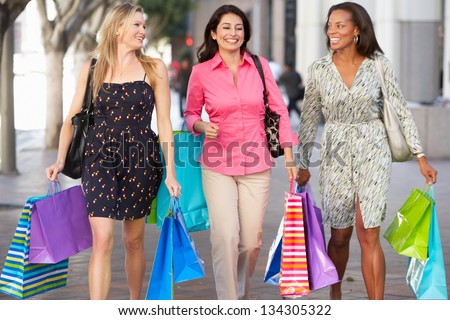 Group Of Women Carrying Shopping Bags On City Street