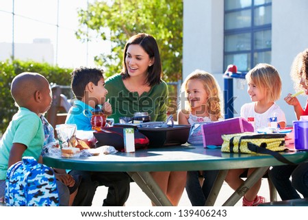 Elementary Pupils And Teacher Eating Lunch