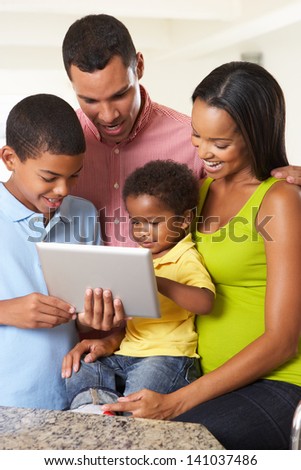 Family Using Digital Tablet In Kitchen Together