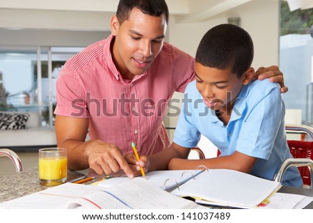 Father Helping Son With Homework In Kitchen