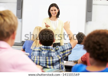 Teacher Standing In Front Of Class Asking Question