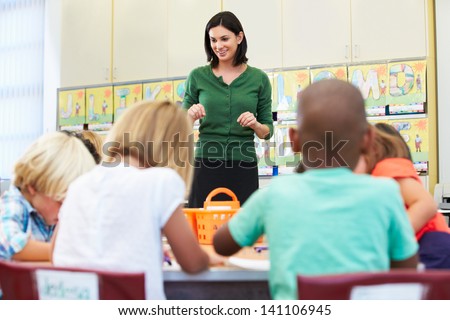 Teacher Talking To Elementary Pupils In Classroom