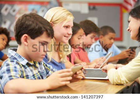 Pupils In Class Using Digital Tablet With Teacher