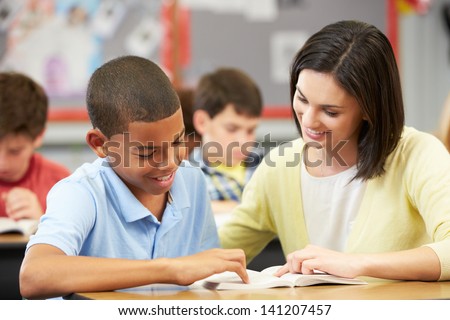 Teacher Reading With Male Pupil In Class