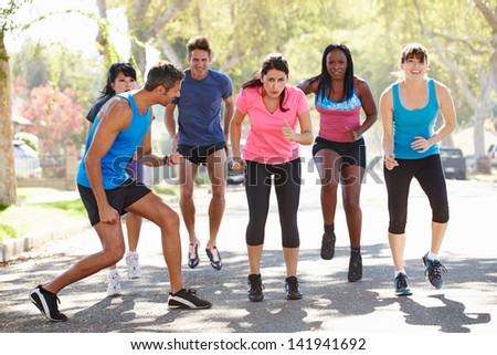 Group Of People Exercising Street With Personal Trainer