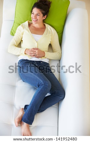 Overhead View Of Woman Relaxing On Sofa Watching Television