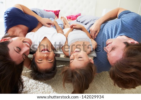 Family Lying Upside Down On Bed In Pajamas Together