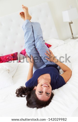 Woman Relaxing In Bed Wearing Pajamas