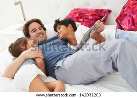 Father And Children Relaxing In Bed Together