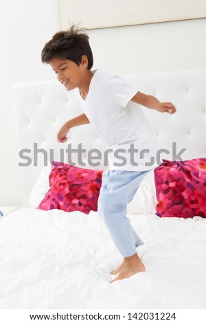 Boy Jumping On Bed Wearing Pajamas