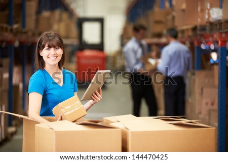 Worker In Warehouse Checking Boxes Using Digital Tablet