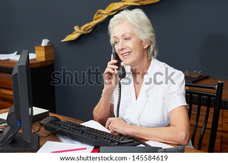 Hotel Receptionist Using Computer And Phone