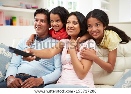 Indian Family Sitting On Sofa Watching Tv Together