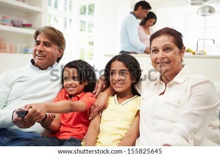 Multi-Generation Indian Family Sitting On Sofa Watching TV