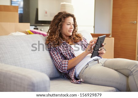 Woman Relaxing On Sofa With Digital Tablet In New Home