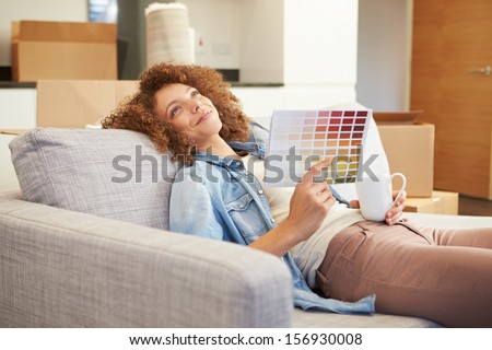 Woman Sitting On Sofa Looking At Paint Charts