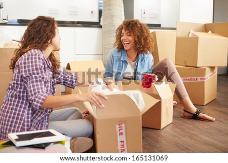 Two Women Moving Into New Home And Unpacking Boxes