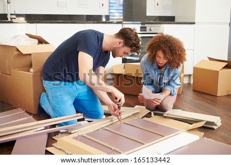 Couple Putting Together Self Assembly Furniture In New Home
