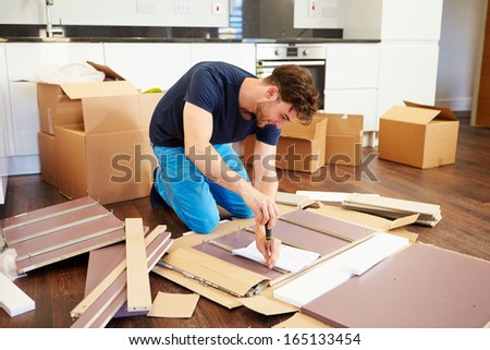Man Putting Together Self Assembly Furniture In New Home