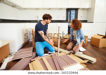 Couple Putting Together Self Assembly Furniture In New Home
