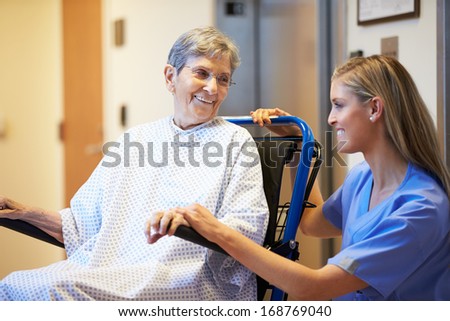 Senior Female Patient Being Pushed In Wheelchair By Nurse