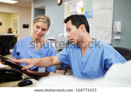 Male And Female Nurse Working At Nurses Station